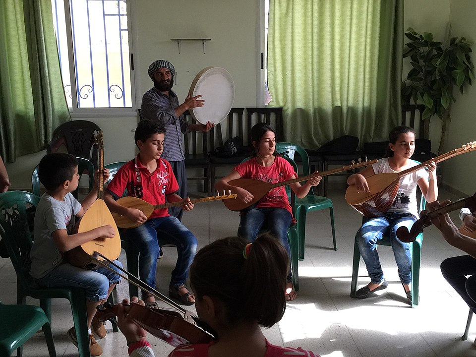 Niños aprendiendo música en escuelas de Rojava